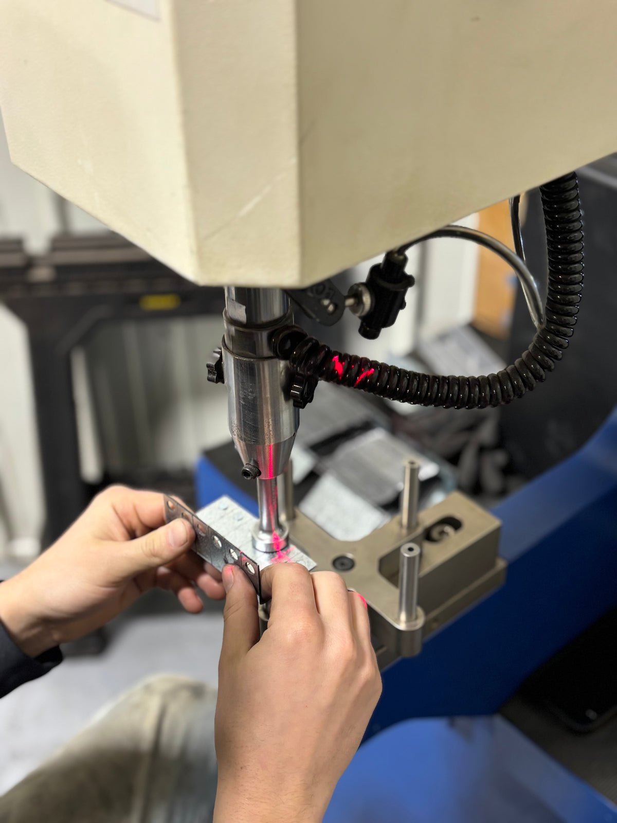 PEM press machine installing threaded inserts into steel L brackets for custom fabrication at HM Metalworks