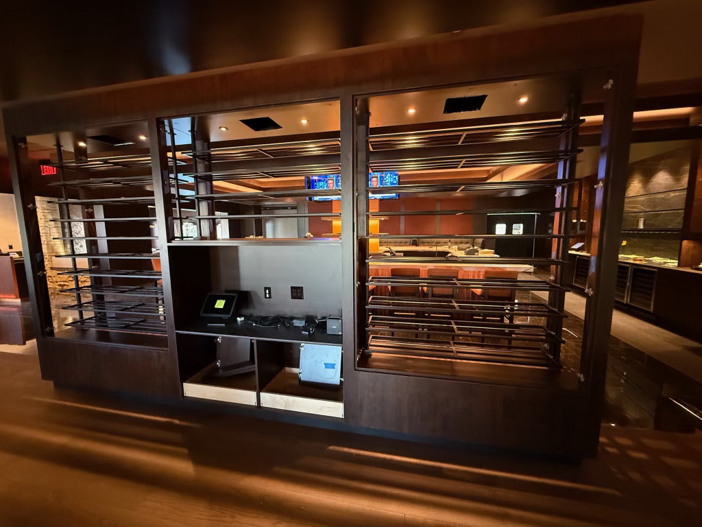 Black metal wine racking set into a wood and glass cabinet at Masseria Italian Steakhouse in Morristown, NJ, built by HM Metalworks